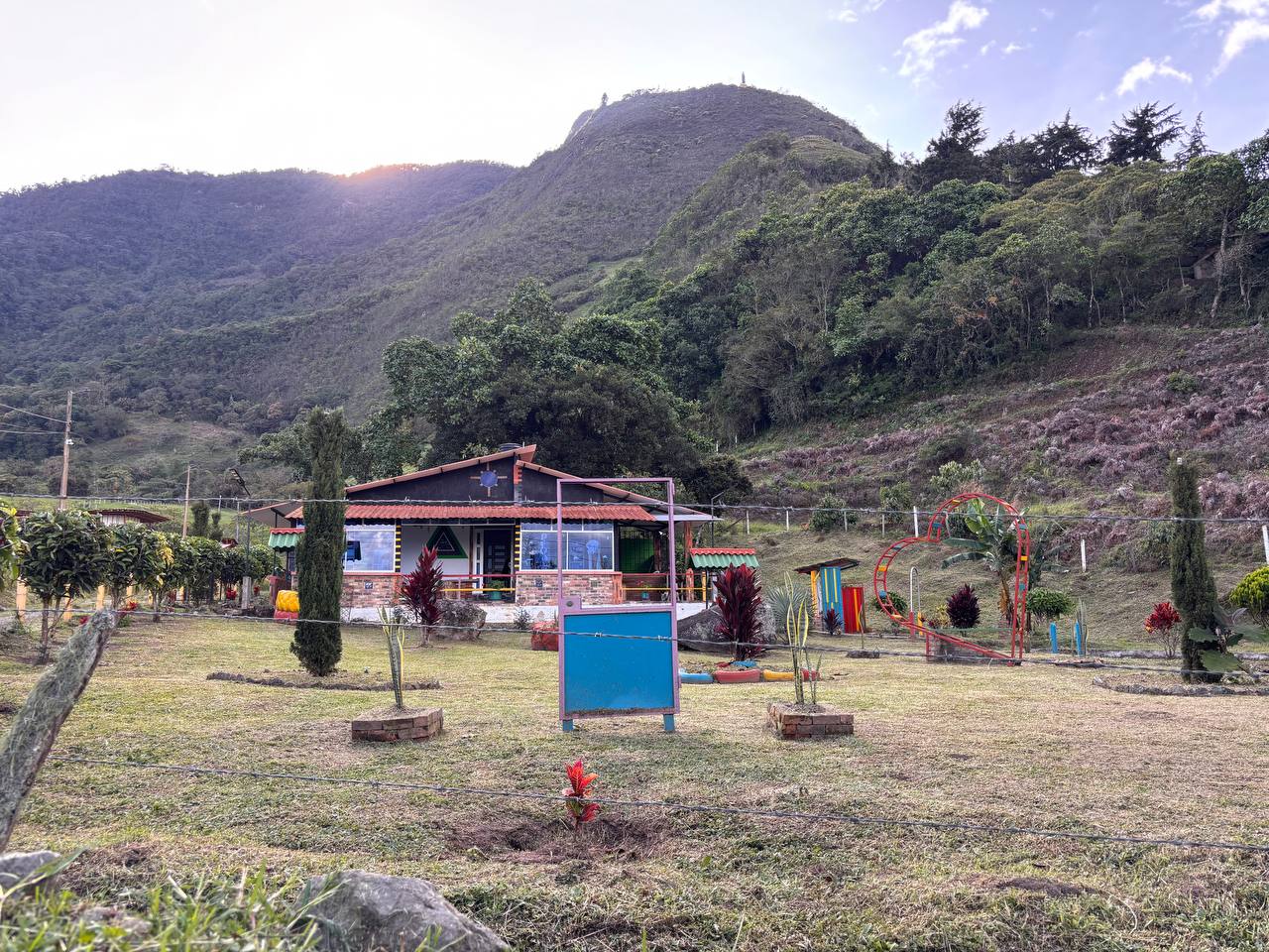 Zona verde de la casa de campo con juegos, jardines y la montaña al fondo
