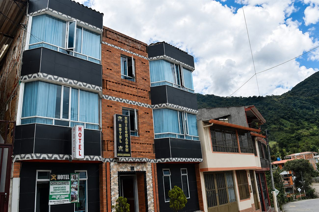 Fachada del Hotel Chibchacum: ladrillo, azulejo negro y el friso muisca en zigzag